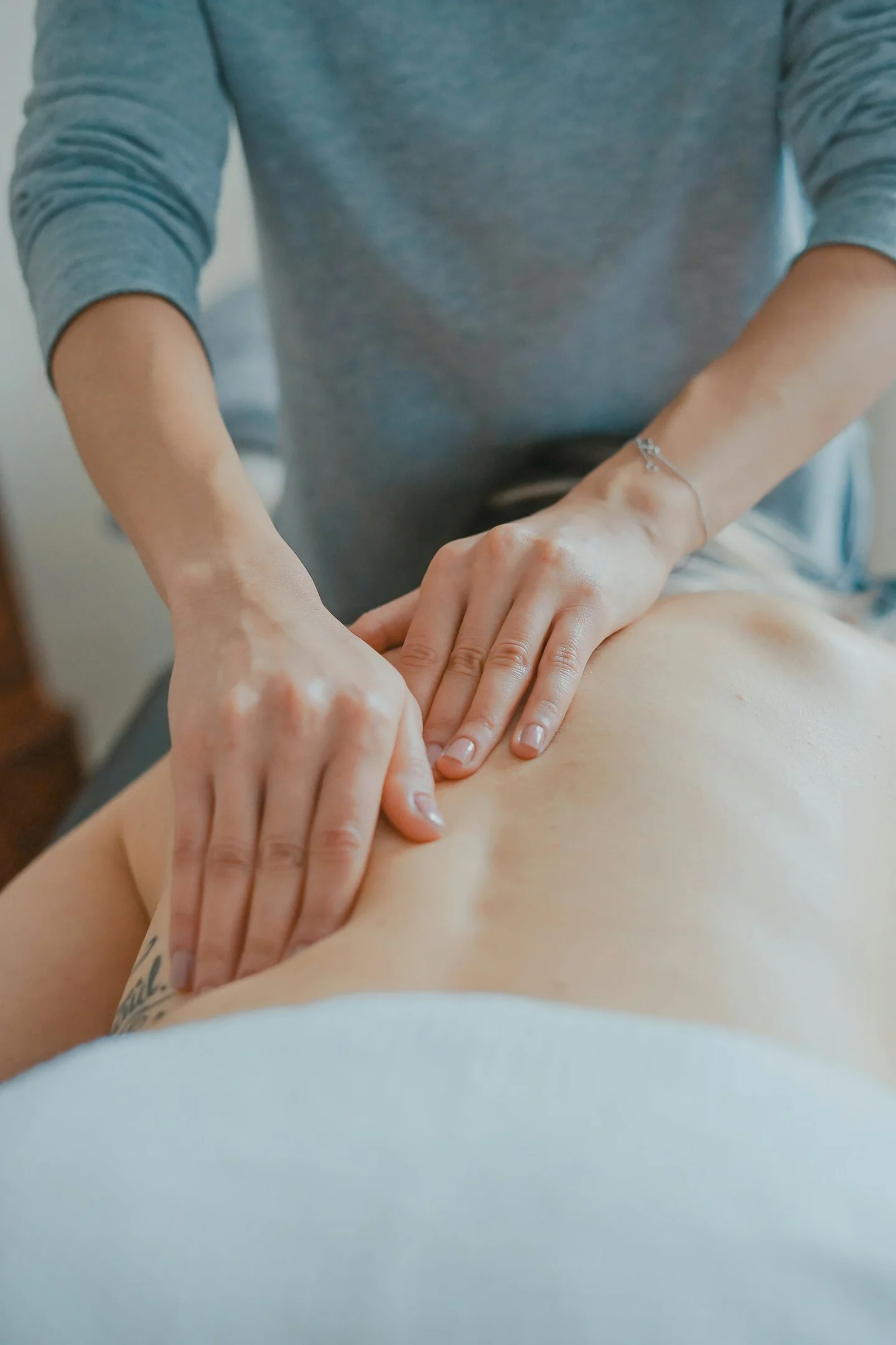 Massage therapist applying firm hand pressure to a client's back
