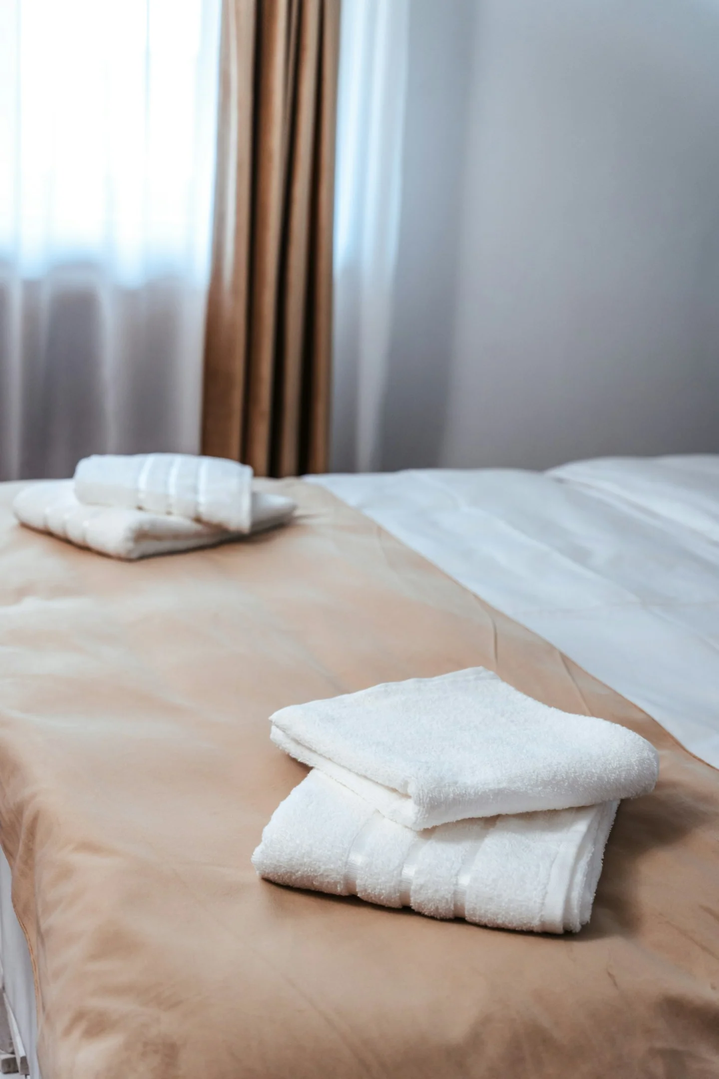 Folded white towels on a bed in a private room