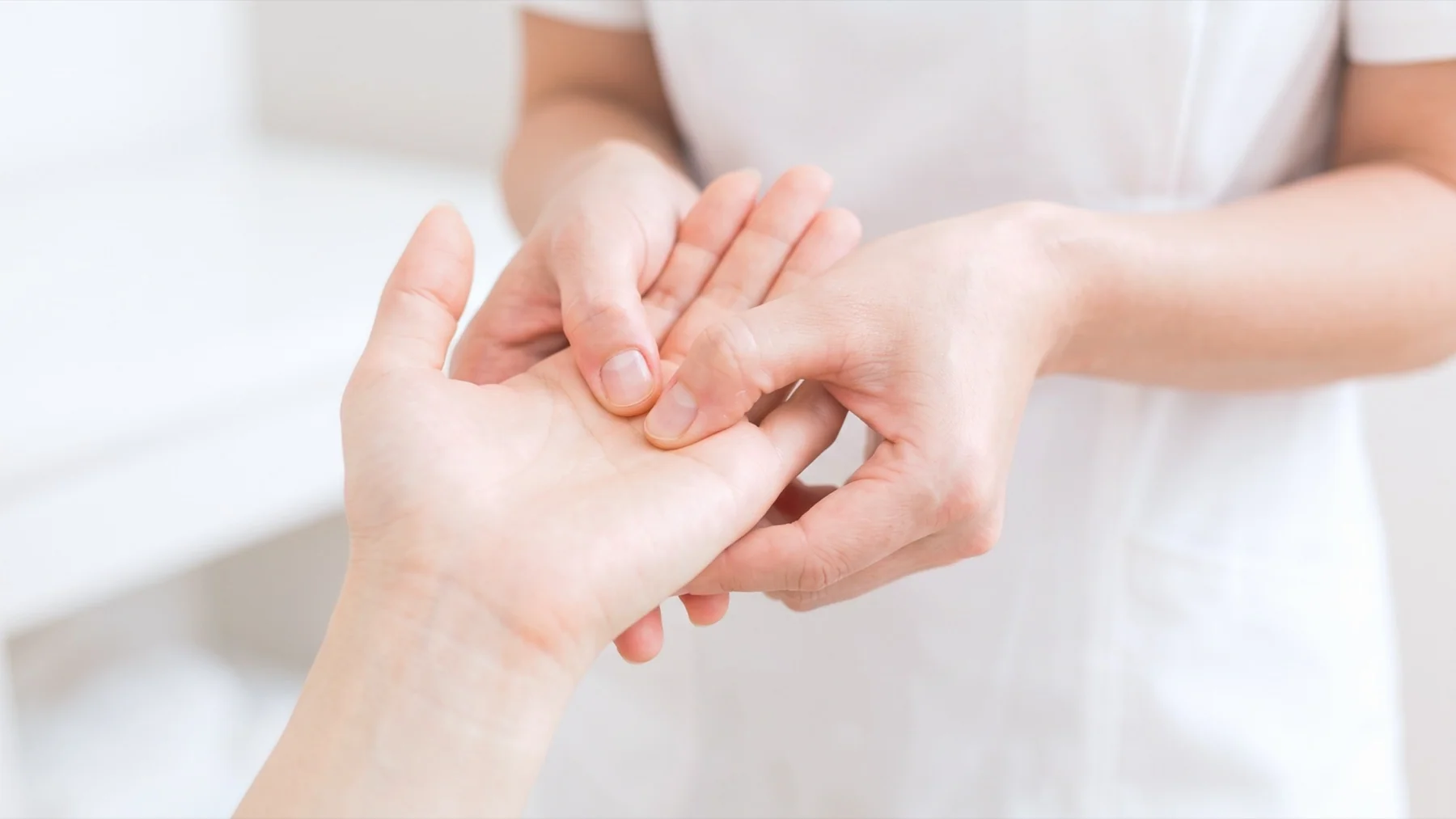 A professional Bednbody massage therapist gently massaging a client's hand in a bright, comfortable home